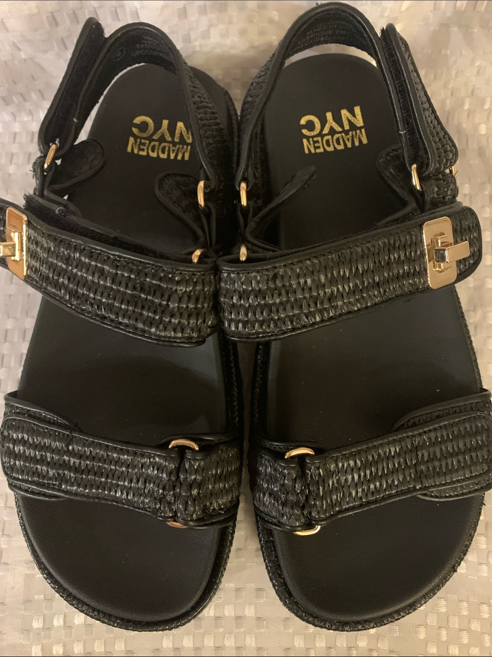 Madden NYC women’s Bigmona black raffia sandals with gold accents, size 8.